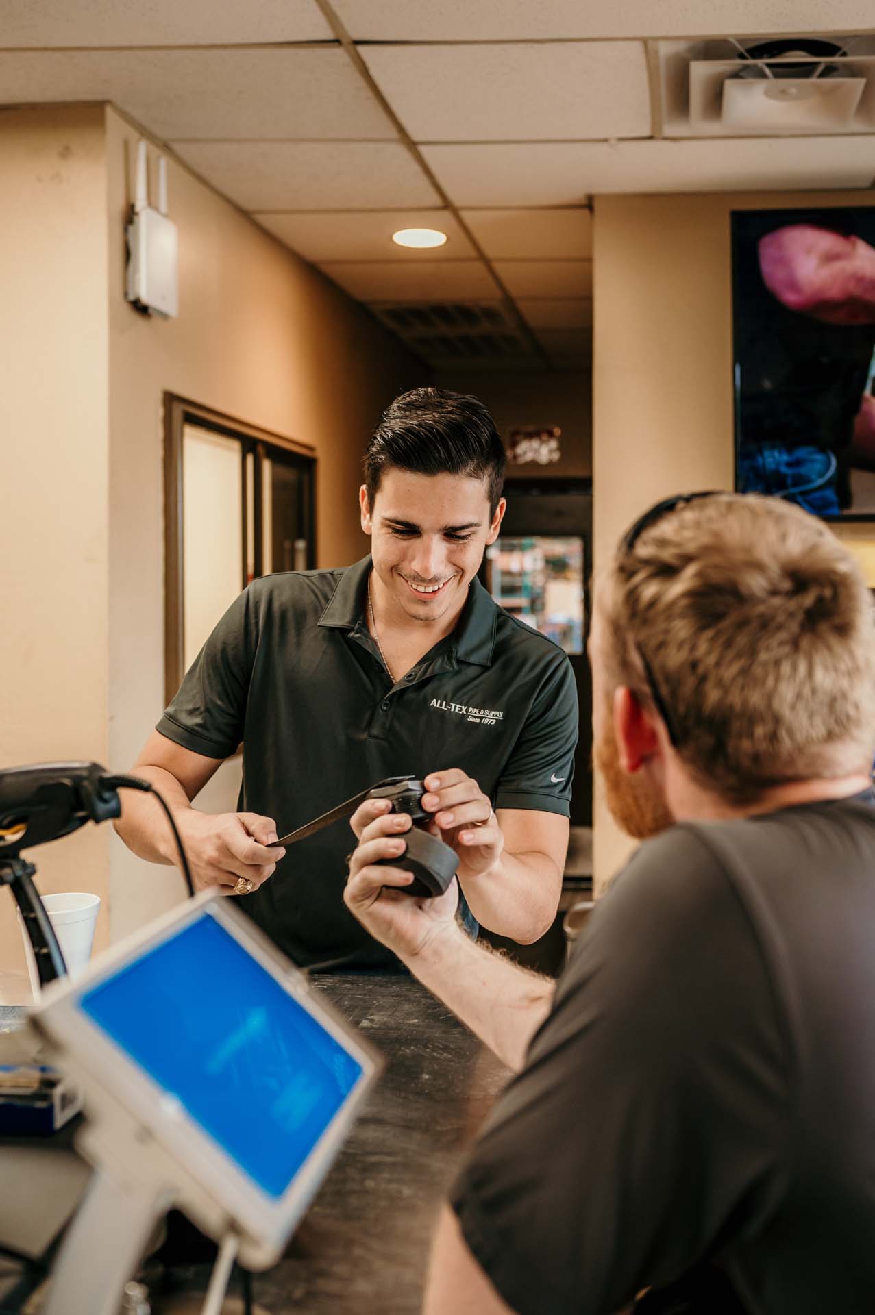 Smiling teammate assisting a contractor at a plumbing supply counter